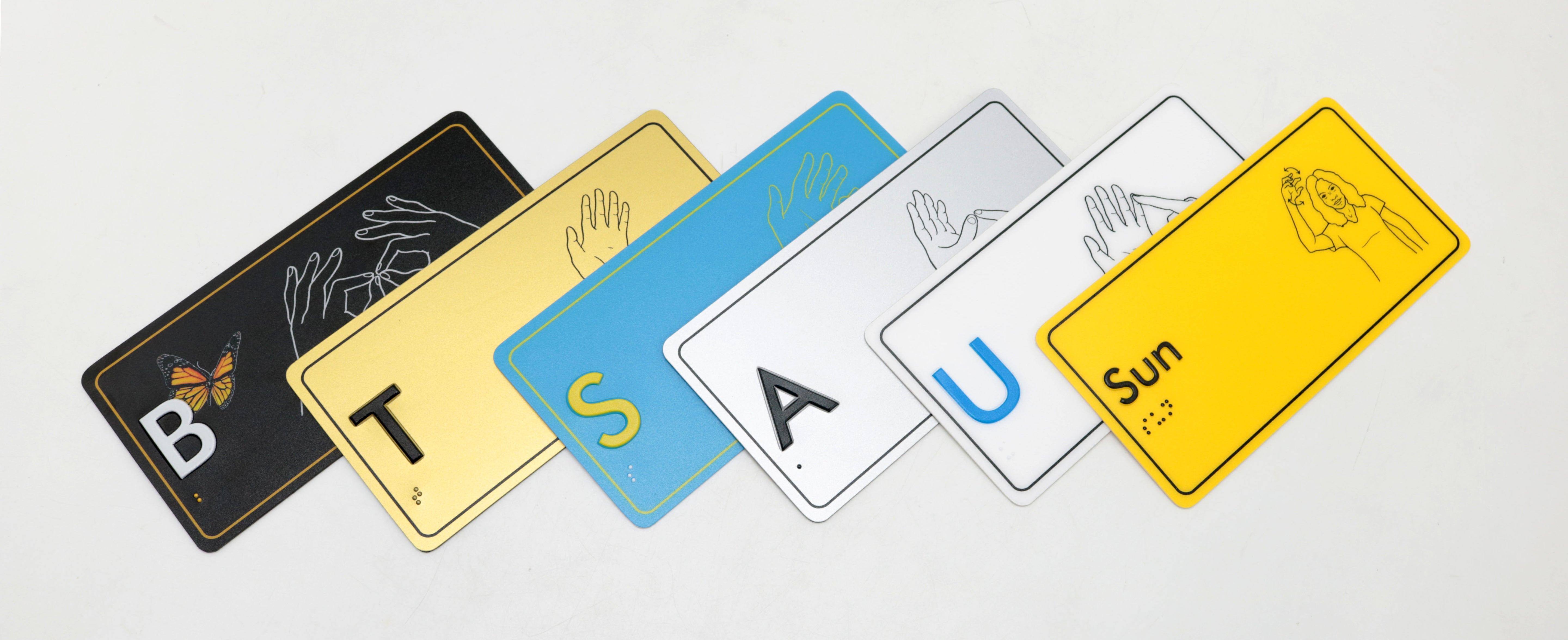 Educational braille signage with letters and AUSLAN hand illustrations.