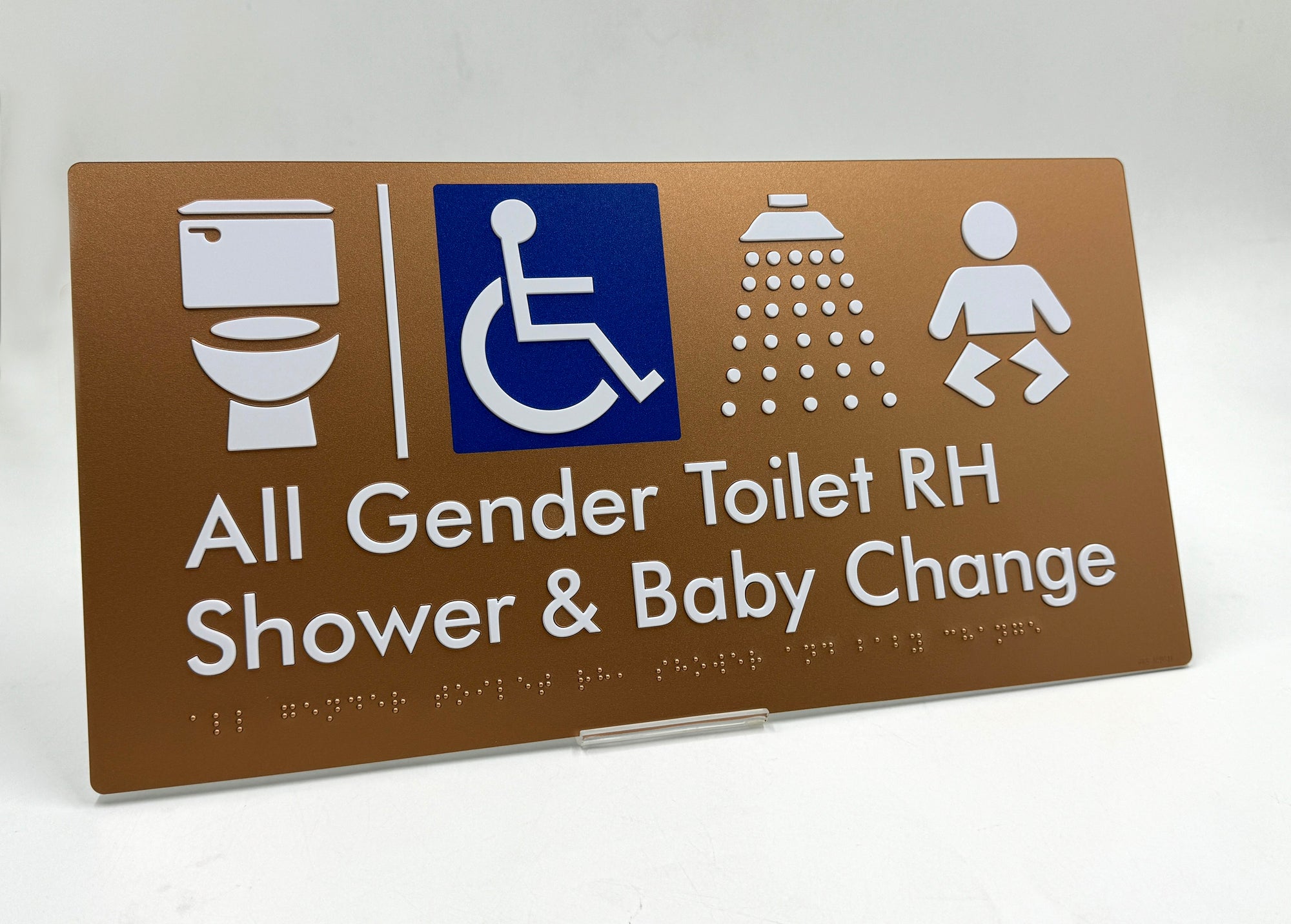 All gender toilet braille sign with accessibility icon, shower, and baby change symbols on a brown background.