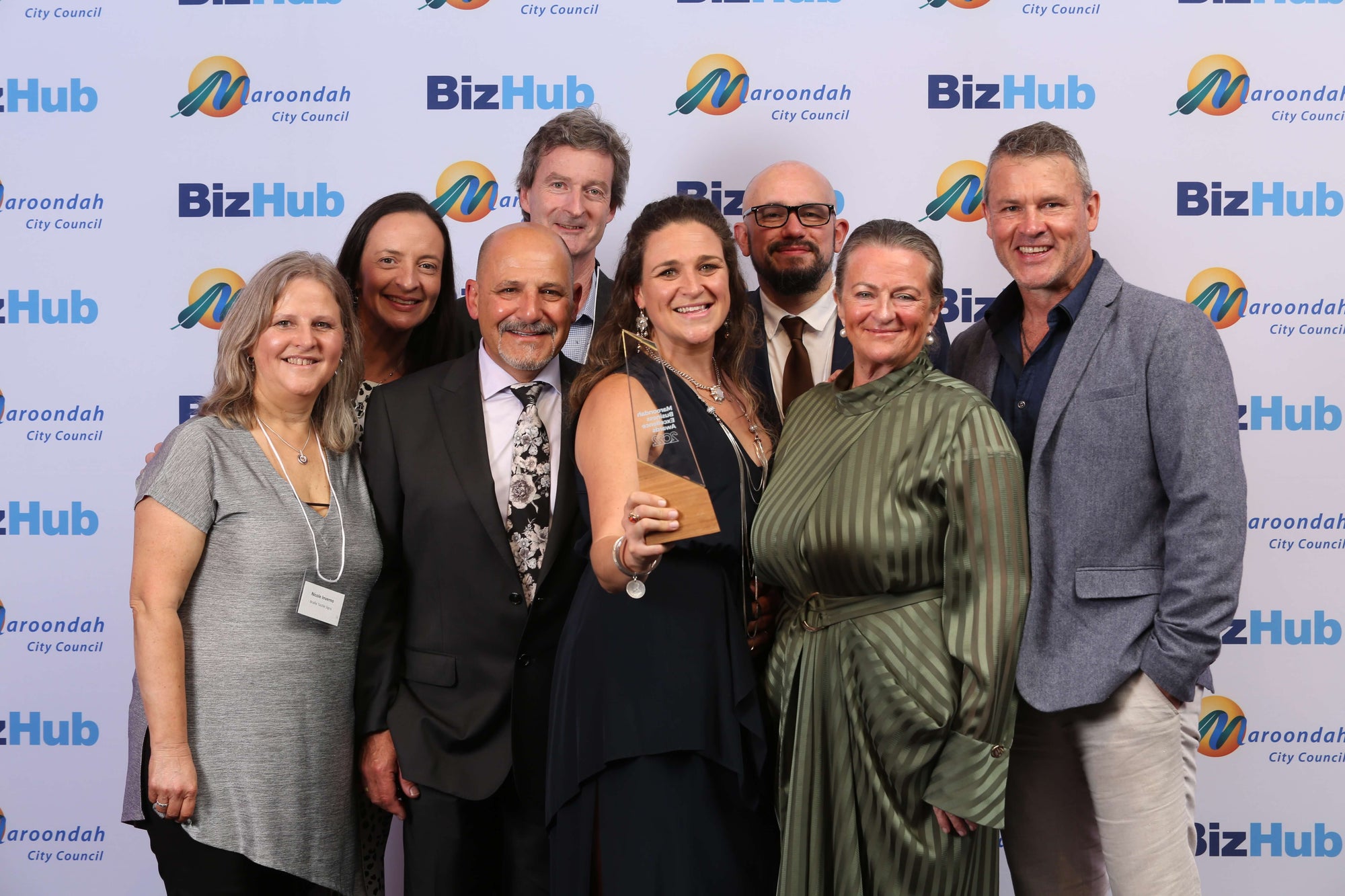 Braille Tactile Signs Aust. team posing with a Business Excellence award against a BizHub and Maroondah City Council backdrop.