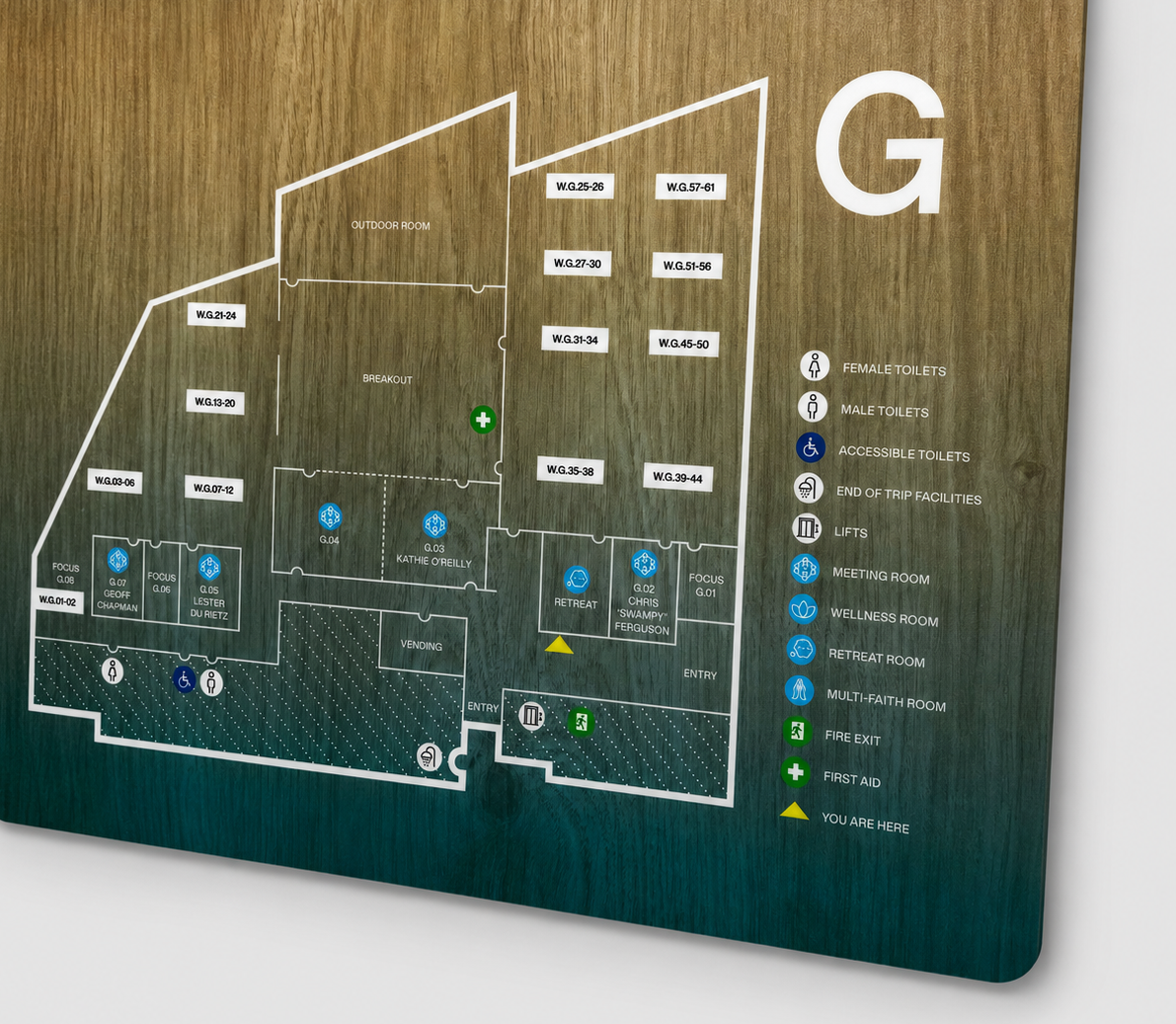 Floor plan of a building with labeled rooms and amenities on a wooden board.