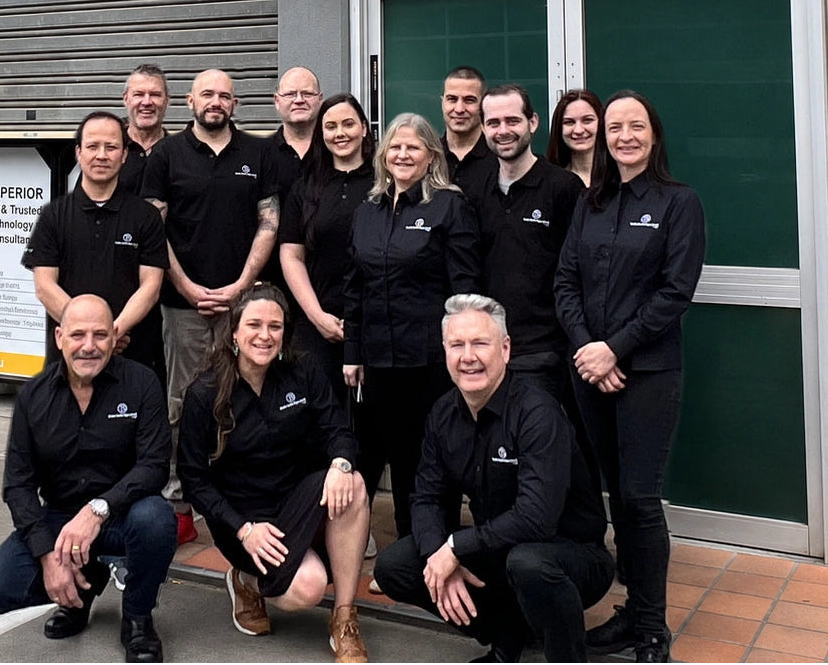 Braille Tactile Signs Aust team in black uniforms posing in front of a building with signage.