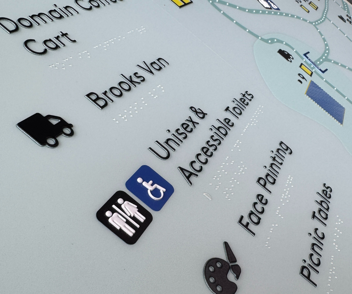 Braille tactile map with icons and text indicating accessible facilities at a venue.