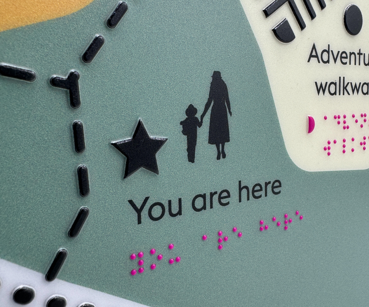 Close-up of a braille tactile map with 'You are here' text and star symbol, featuring tactile design elements.