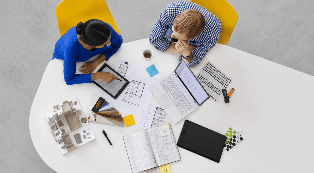 Two colleagues discussing design plans for Braille Tactile Signage and Wayfinding at a desk