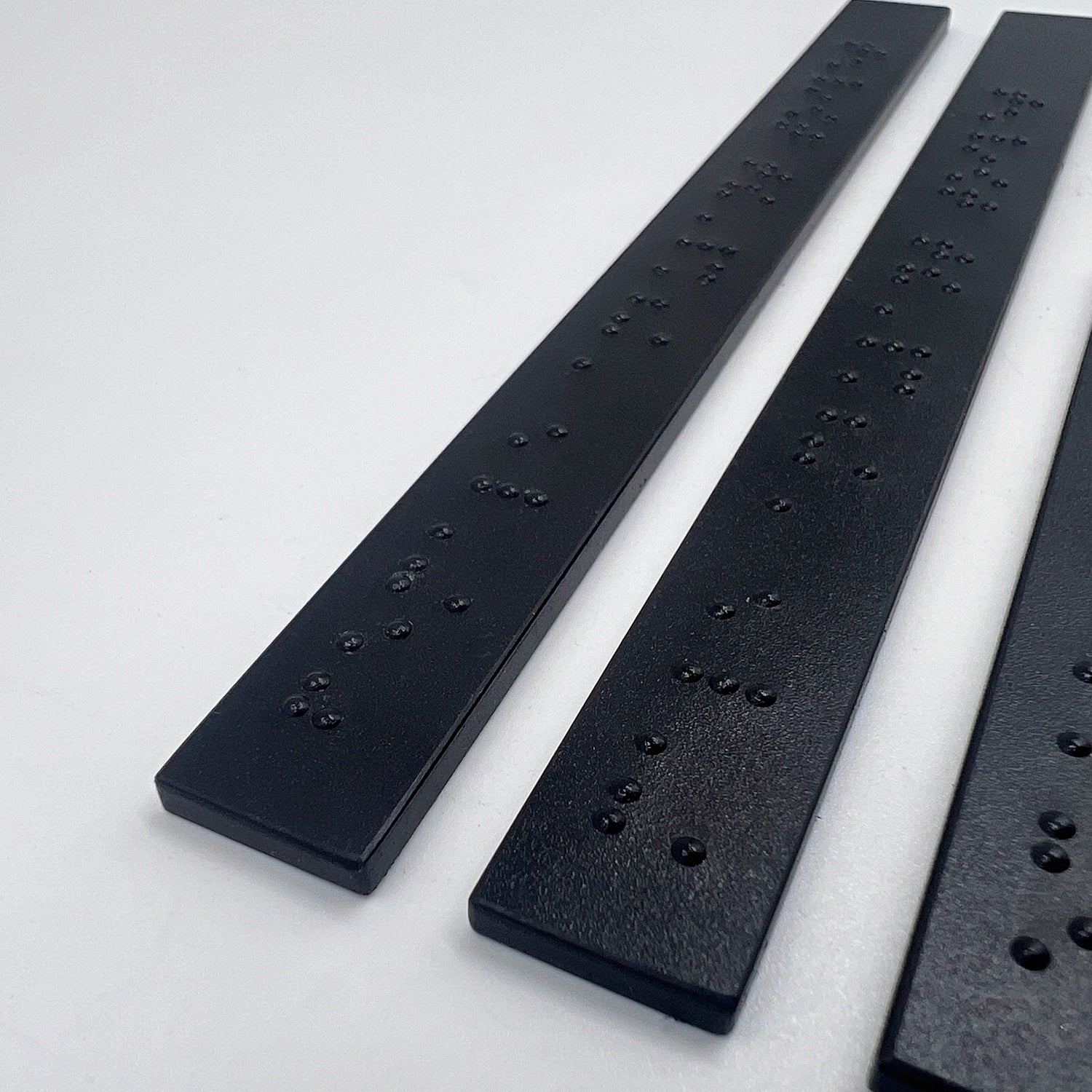 Close up of 3 black braille strips