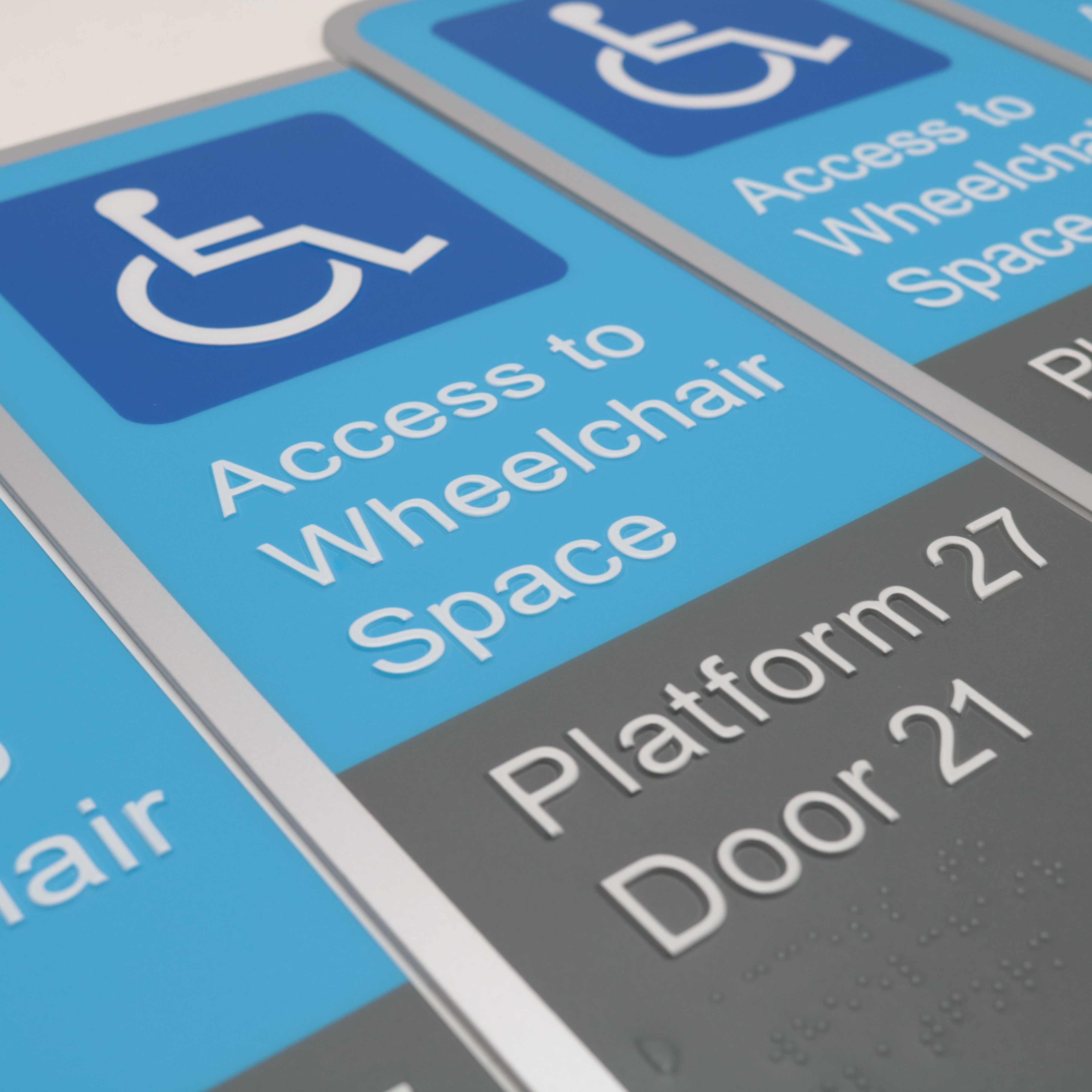 Close-up of accessibility braille signs with wheelchair symbol and text.