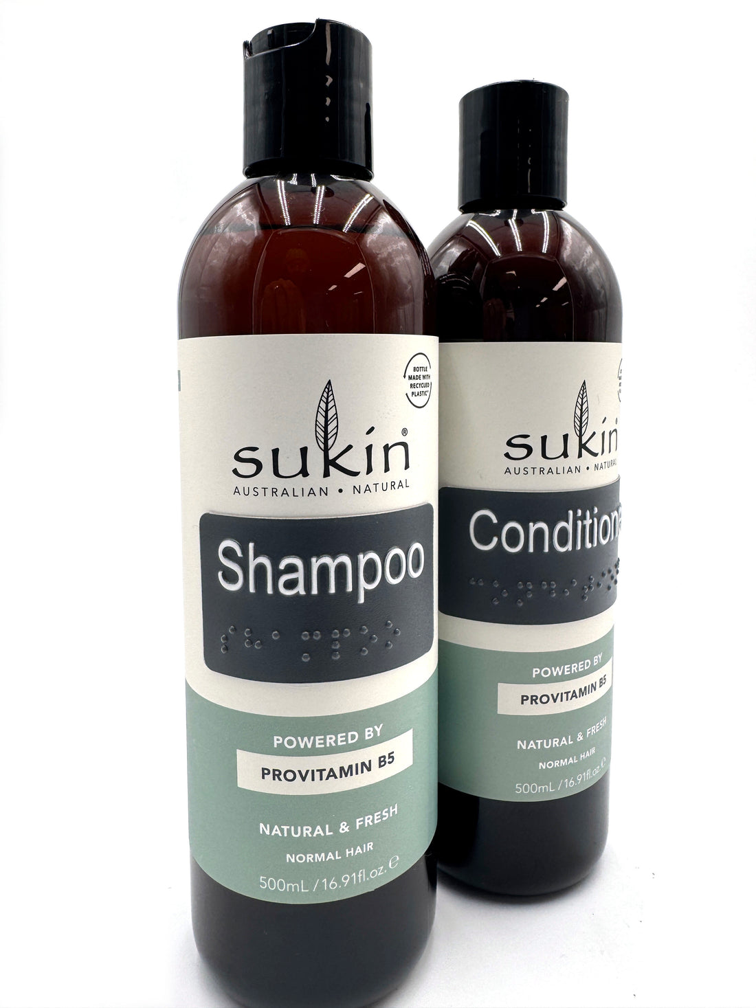 Sukin shampoo and conditioner bottles with braille labels.