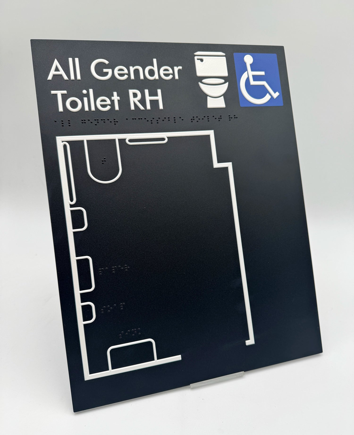 Black tactile 'All Gender Toilet' sign with white outline of a toilet plan.