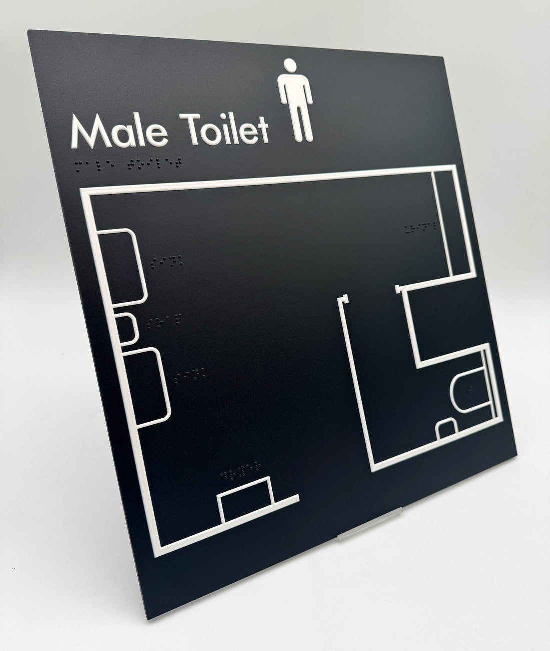 Black tactile sign with white outline of a male toilet plan on a gray background.