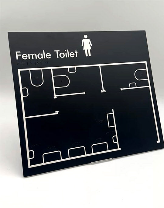 Black tactile sign with white outline of a female toilet plan.