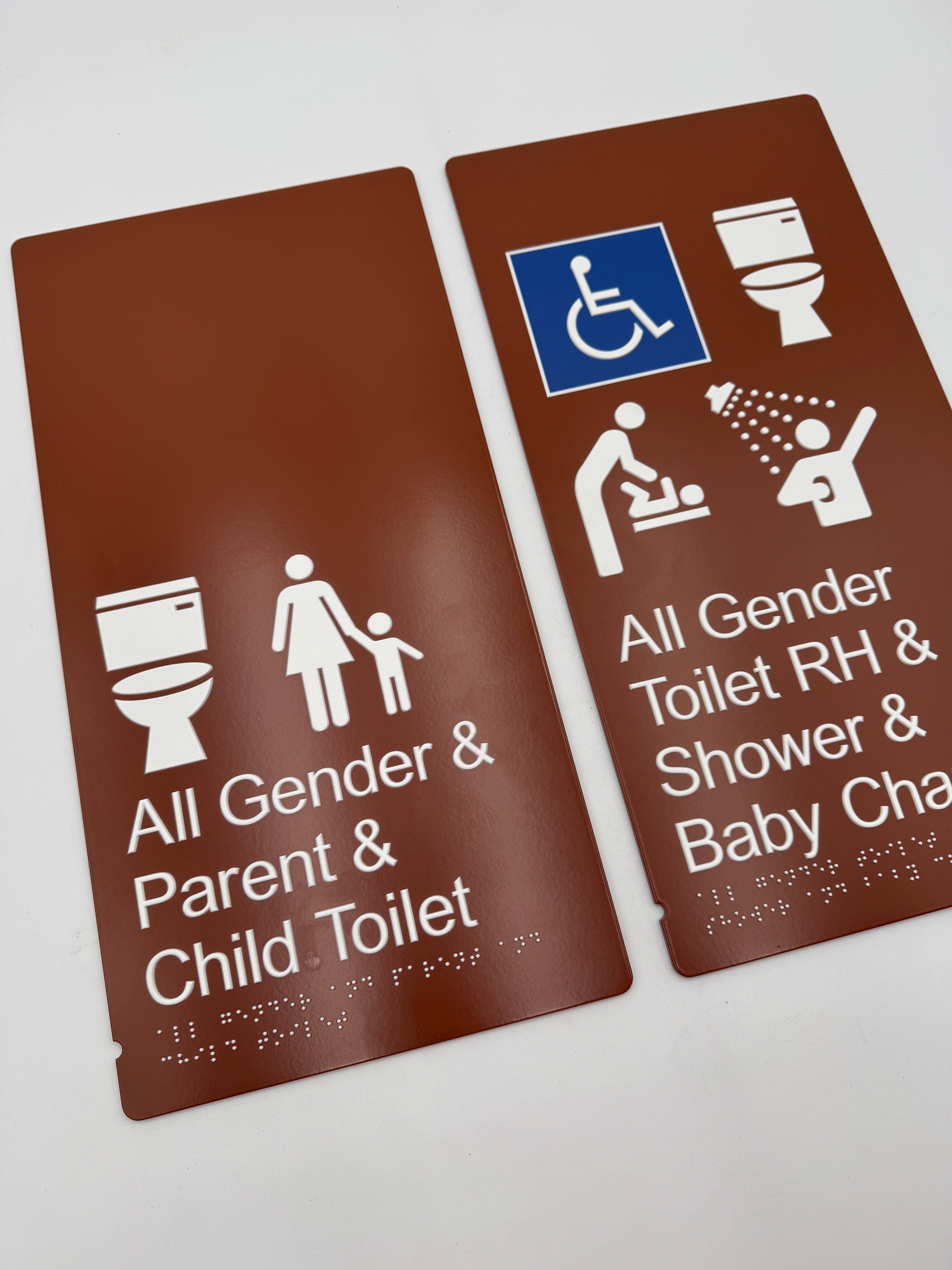 Two brown braille signswith accessibility icons and text.