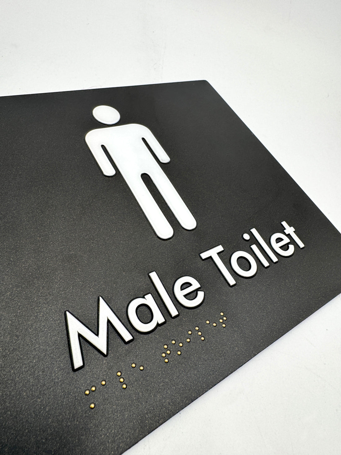 Black braille signs with white male symbol and 'Male Toilet' text on a white background