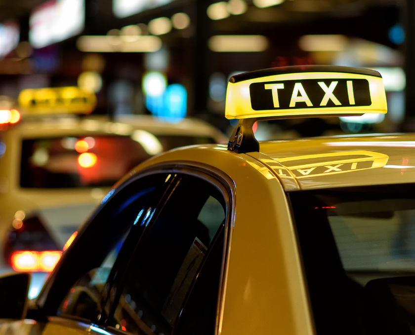 Taxi with illuminated sign on a blurred city street background